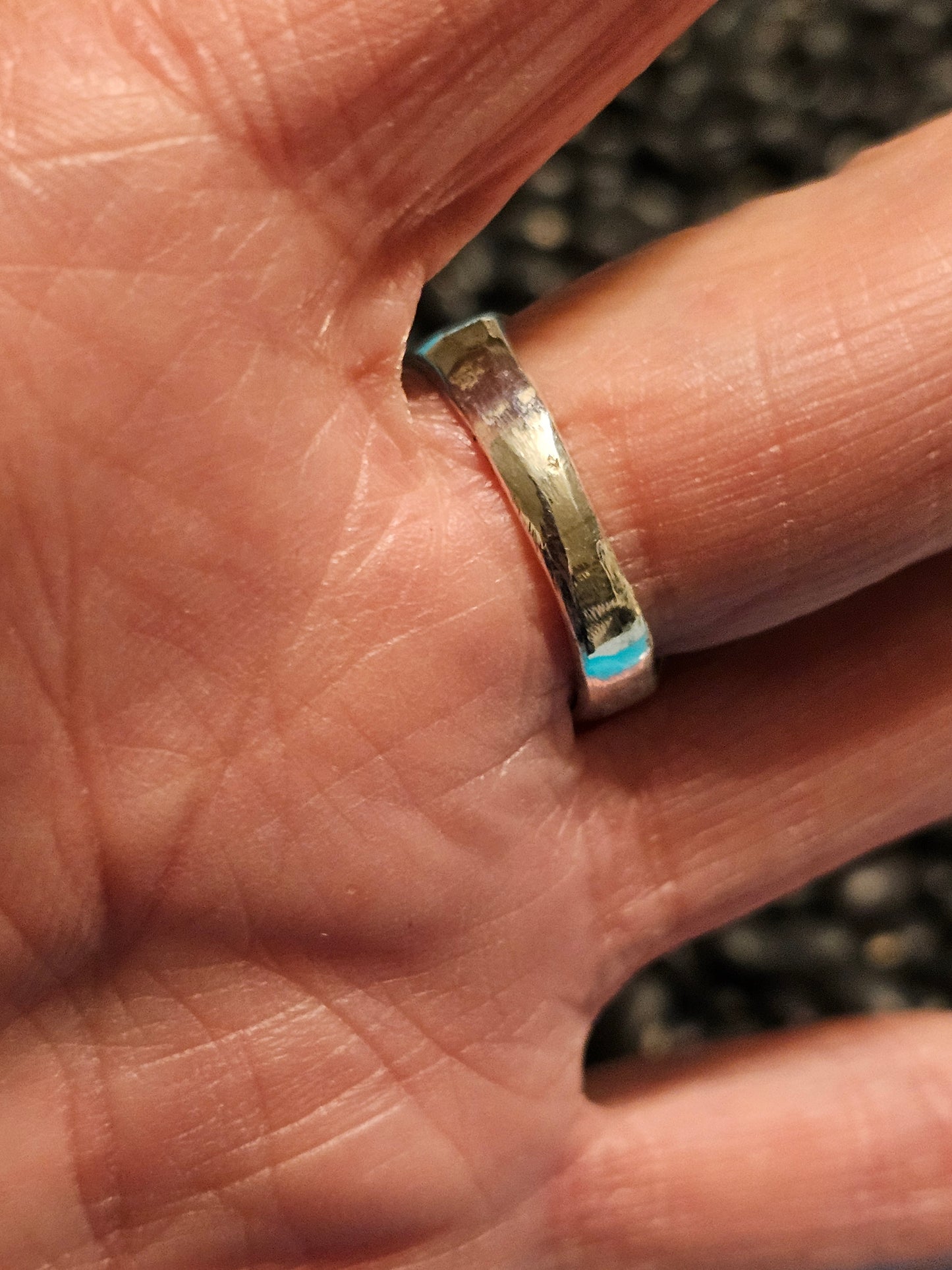 Silver ring on a person's finger with a blurred background